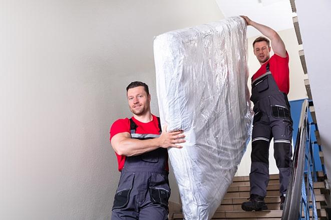 heavy lifting as a box spring is carried away for disposal in Bucoda